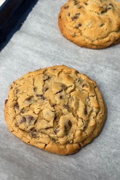 two chocolate chip cookies sitting on top of a baking sheet