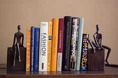 a bookshelf filled with lots of books next to a small statue on top of it