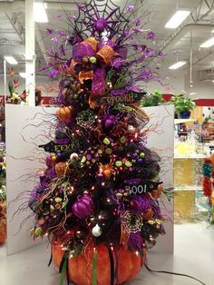 a purple and orange christmas tree with decorations on it in a store display area,