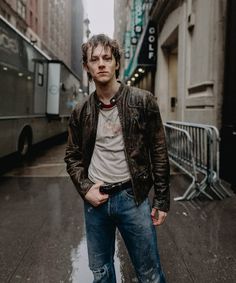 a man standing in the middle of a city street with his hands in his pockets