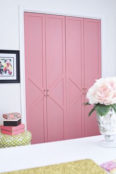 a bedroom with pink closets and flowers in the vase on the bed's headboard