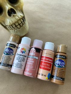 the skull is next to five different colors of acrylic paint