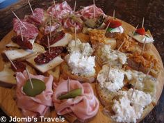 an assortment of appetizers are arranged on a wooden platter