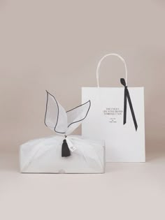 a white paper bag with a black ribbon tied around it and an ornament hanging from the handle