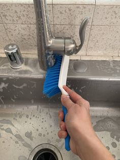 a hand holding a blue brush over a sink