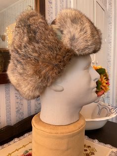 "Made for Crown Cap, this hat is made of durable nylon in light greenish beige, with soft, warm rabbit fur in natural shades of light to dark brown trimming the hat and lining the inside of the neck protector and ear flaps. This hat has mini ear flaps under the larger ones that can be lifted to reveal the \"listening hole\" underneath. There are two snaps on the brim, and the hat is lined with brown satiny fabric lining. Fits men's size 6 7/8 or small. In very good condition." Warm Faux Fur Hats With Ear Flaps, Crown Cap, Brown Trim, Trapper Hats, Rabbit Fur, Beige Aesthetic, Natural Shades, Fur Trim, Caps Hats