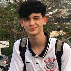 a young man wearing a white shirt and black suspenders is smiling at the camera