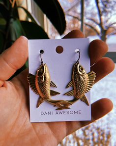 Dive into the enchanting depths of my Brass Fish Earrings - the aquatic accessory that's got everyone channeling their inner Pisces vibes. These earrings are swimming into your collection at a cool price. **Dimensions At 2.25 inches long and 1.5 inches wide, these earrings make a statement without shouting. Perfect for those who prefer a touch of animal allure in their accessories. **Crafted with a Dash of Magic These earrings boast a concoction of materials, including: - *Raw Brass Fish Charm:* The star of the show, this fish charm brings a dash of magic and a whole lot of cool to your ear game. - *Antique Gold Plated Steel Ear Wire:* Secure, stylish, and just the right amount of vintage charm. - *Rubber Earring Back:* Because we know you've got places to go and spells to cast - these rub Brass Jewelry With Fish Hook For Gift, Gold Fish-shaped Earrings With Fish Hook, Pisces Earrings, Pisces Vibes, Witches Broomsticks, Fish Earrings, Beta Fish, Sea Witch, Witchy Jewelry