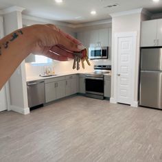 a person is holding keys in their hand while standing in the middle of a kitchen