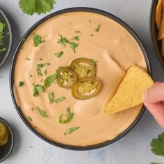 a person dipping tortilla chips into a bowl of dip