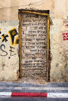 an old brick wall with graffiti on it and a door in the middle that has writing on it