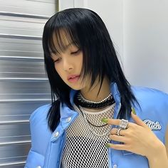 a woman with black hair wearing a blue jacket and holding a cell phone in her hand