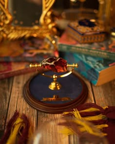 a small golden clock sitting on top of a wooden table next to books and tassels