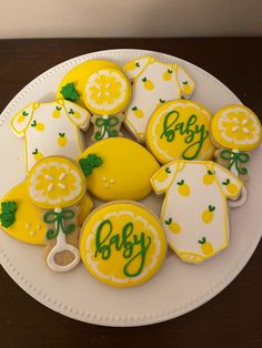 a white plate topped with cookies covered in icing and decorated lemons on top of a wooden table