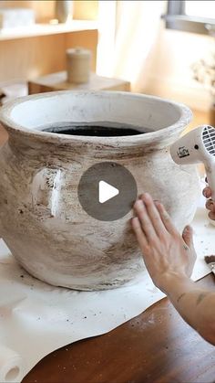 a person is using a remote control to make a large pot with dirt on it