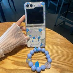 a person holding up a cell phone case with blue beads and an umbrella on the table