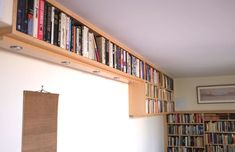 a bookshelf filled with lots of books next to a white wall