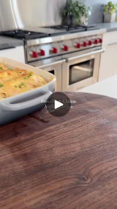 a bowl of food sitting on top of a wooden table next to an oven and stove