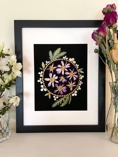 some flowers are in vases on a shelf next to a black and white frame