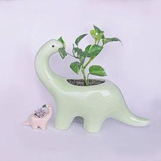 an elephant planter is next to a small toy dinosaur