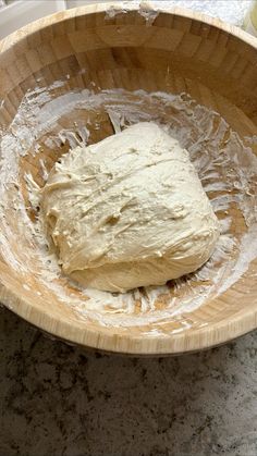 a wooden bowl filled with dough on top of a counter