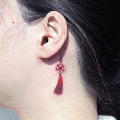 a close up of a woman's ear with a flower and tassel on it