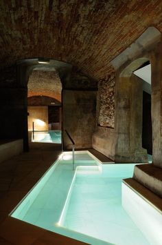 an indoor swimming pool surrounded by stone walls