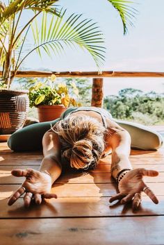 a woman is doing yoga on the deck with her hands and legs spread out in front of her