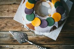 a cake with icing and colored circles on it next to a spatula knife