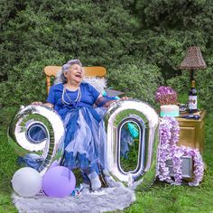 an older woman sitting in a chair with balloons and streamers around her, surrounded by letters that spell out the number 90