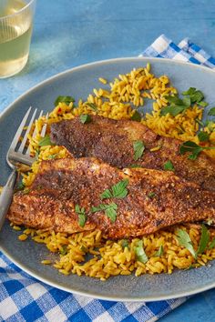 two pieces of fish on top of yellow rice and garnished with parsley