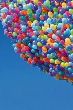 a bunch of balloons floating in the air with a blue sky behind them and a plane flying overhead