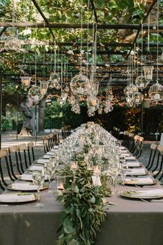 a long table is set with plates and place settings for an outdoor dinner party in the garden