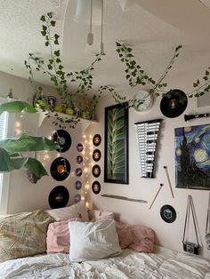 a bedroom with plants hanging from the ceiling and various records on the wall above the bed