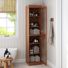 a wooden cabinet in a bathroom with towels and bottles on the shelf next to it