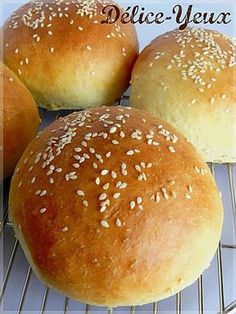 three buns with sesame seeds sitting on a cooling rack