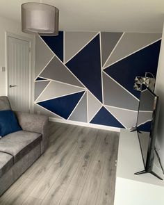 a living room with a gray couch and blue accents on the wall, next to a lamp