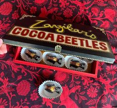 an open box with chocolates in it sitting on a red and pink table cloth