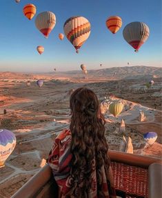 a woman looking at hot air balloons in the sky