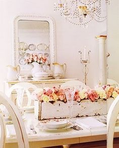 a dining room table with flowers on it and a chandelier hanging from the ceiling