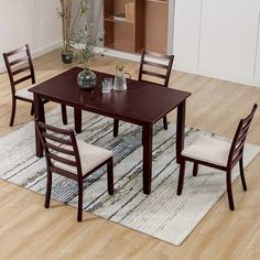 a dining room table with four chairs and a rug on the floor