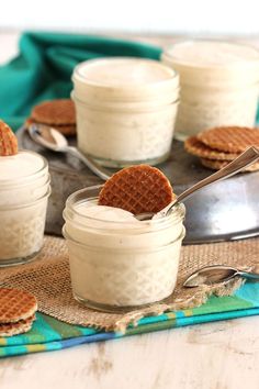 some cookies and cream in small jars with spoons on a table next to them