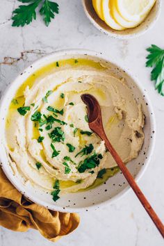 a white bowl filled with hummus and parsley on top of a marble table