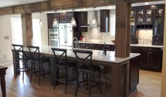 a kitchen with an island and bar stools in the center, surrounded by dark wood cabinets