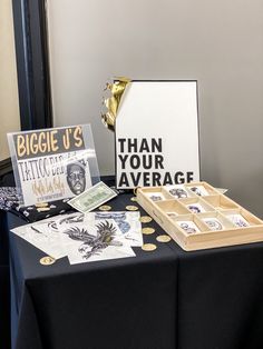 the table is set up for an event with black and white decorations, gold confetti, and greeting cards