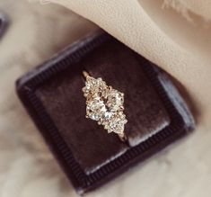 a diamond ring sitting on top of a velvet box next to a white cloth napkin