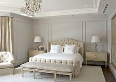 a large white bed sitting in a bedroom next to two chairs and a chandelier