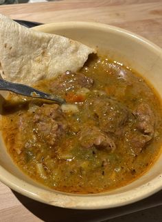 a white bowl filled with soup and a tortilla on top of the bowl