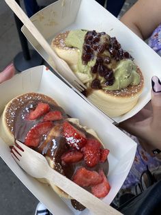 two people holding open boxes with pastries and strawberries in them on the street