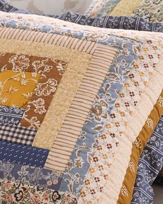 a close up of a quilted bed with blue and yellow colors on it's sides